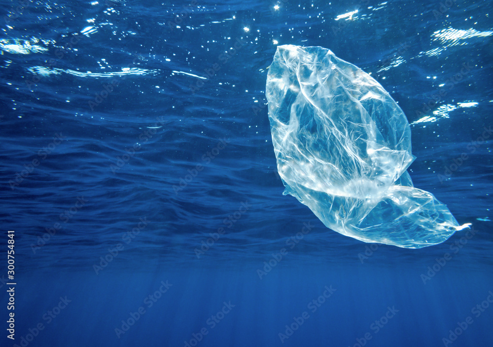 A polyethylene bag floats in the open sea underwater in sun rays. A polyethylene bag floats in the open sea underwater in sun rays.