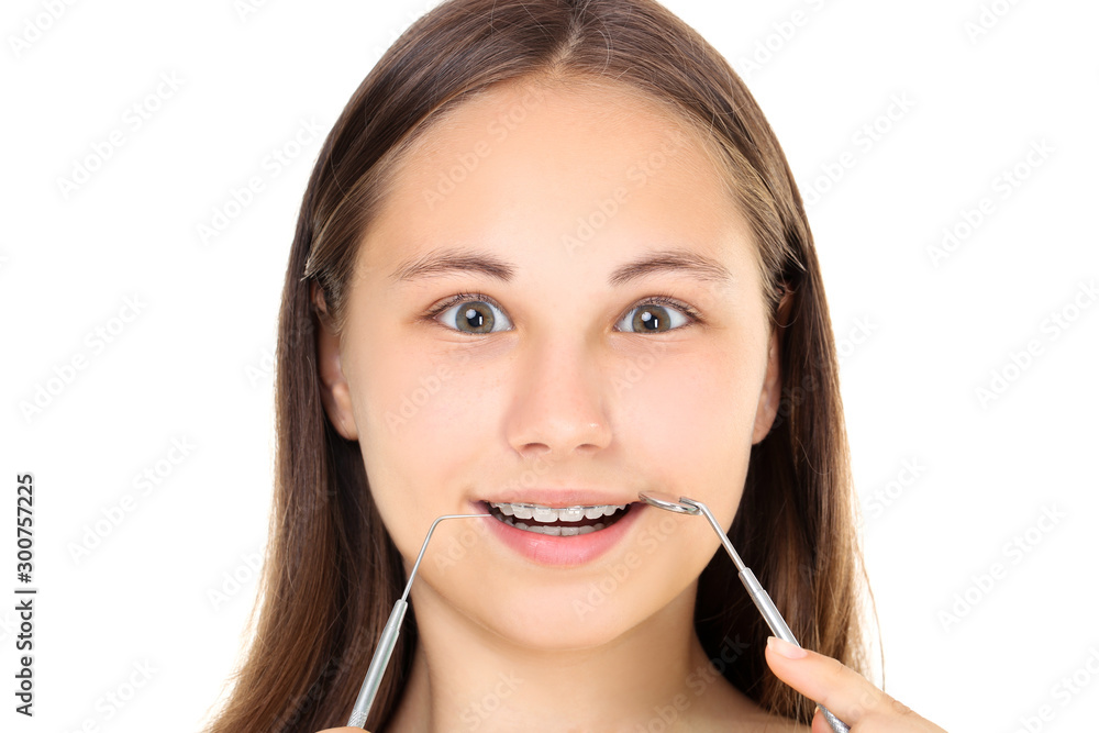 Young girl with dental braces holding dentist tools on white background Young girl with dental braces holding dentist tools on white background