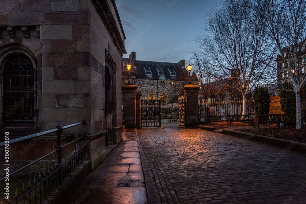 GLASGOW, SCOTLAND, DECEMBER 16, 2018: Beautiful cobbled street surrounded by old European style buildings. Illuminated only with weak light from street lamps. GLASGOW, SCOTLAND, DECEMBER 16, 2018: Beautiful cobbled street surrounded by old European style buildings. Illuminated only with weak light from street lamps.