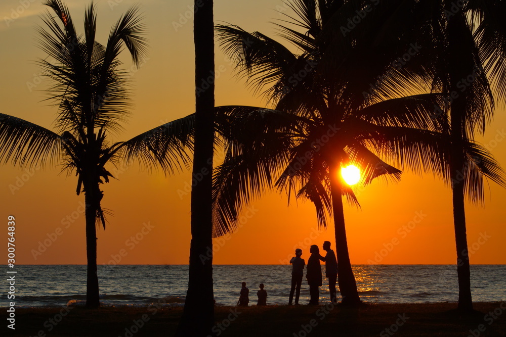 Beautiful sunset with silhouette tree and people at beach