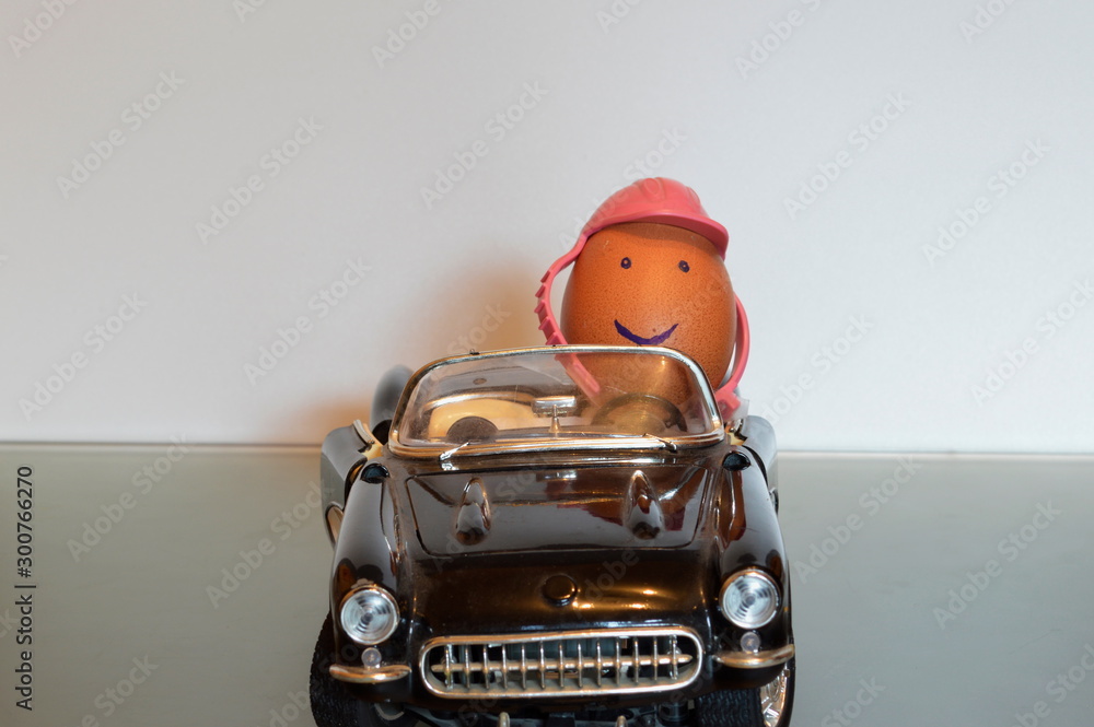 An egg driving a convertible car wearing a helmet as a symbol for road