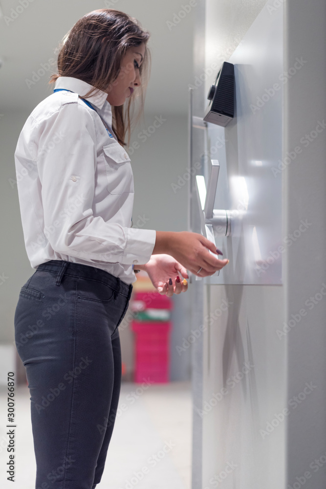 Businesswoman bank employee  bank vault door typing security code for alarm system.