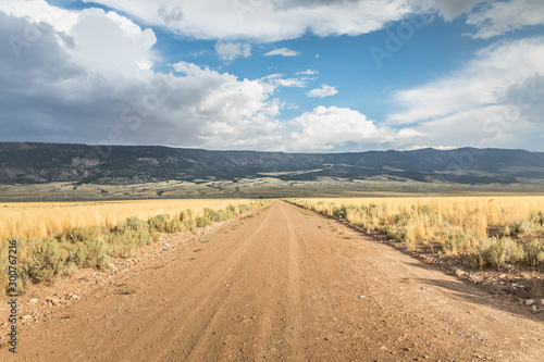 Long straight dirt road in Utah with dramatic clouds