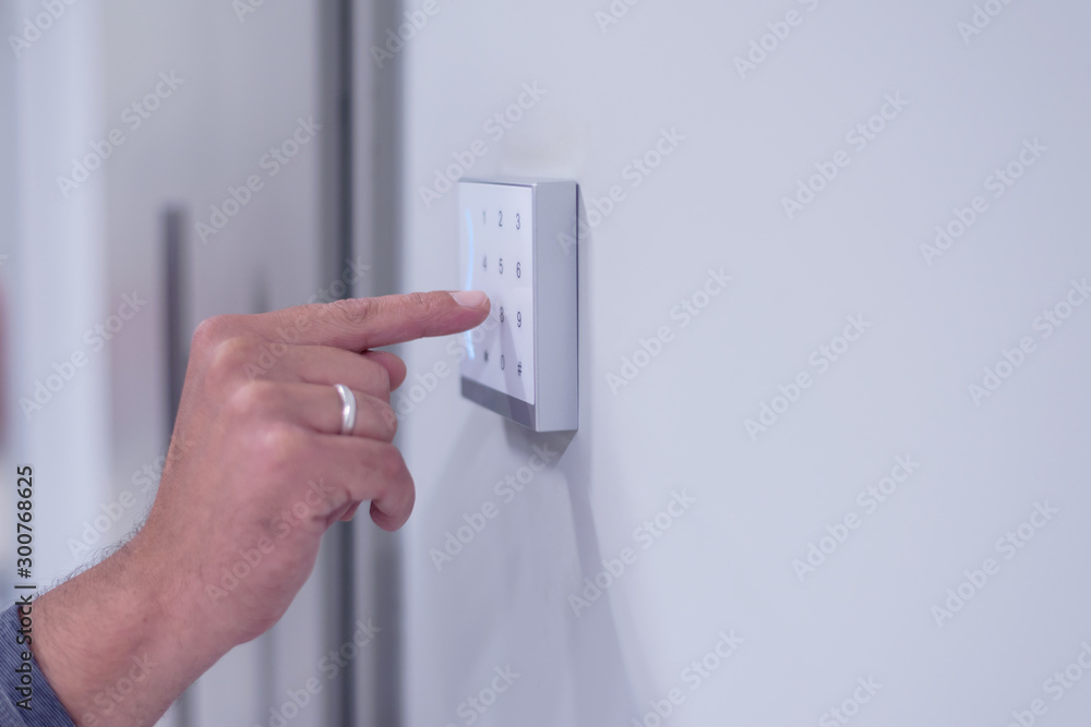 Young businessman entering access code at building entrance. The smart home system with access control for entering a PIN code. A hand is typing a combination on the keyboard. Young businessman entering access code at building entrance. The smart home system with access control for entering a PIN code. A hand is typing a combination on the keyboard.