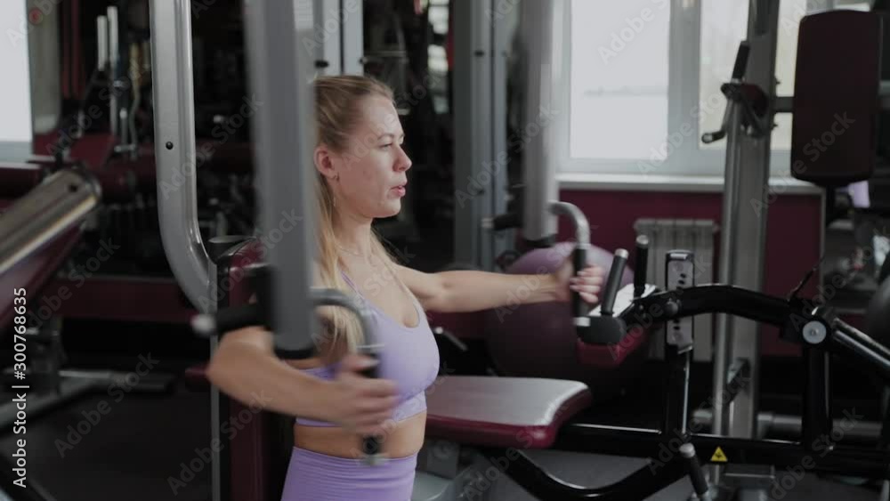 Athletic woman with a beautiful figure trains pectoral muscles on the simulator in the gym. Athletic woman with a beautiful figure trains pectoral muscles on the simulator in the gym.