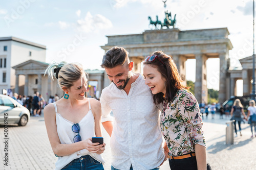 Three friends looking at cell phone in front of Brandenburger Tor, Berlin, Germany photo