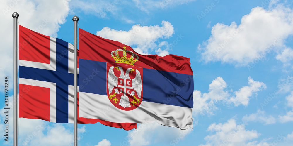 Bouvet Islands and Serbia flag waving in the wind against white cloudy blue sky together. Diplomacy concept, international relations.