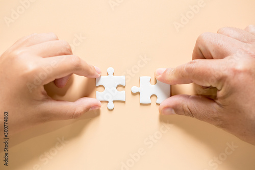 hand connecting two puzzle pieces on table background