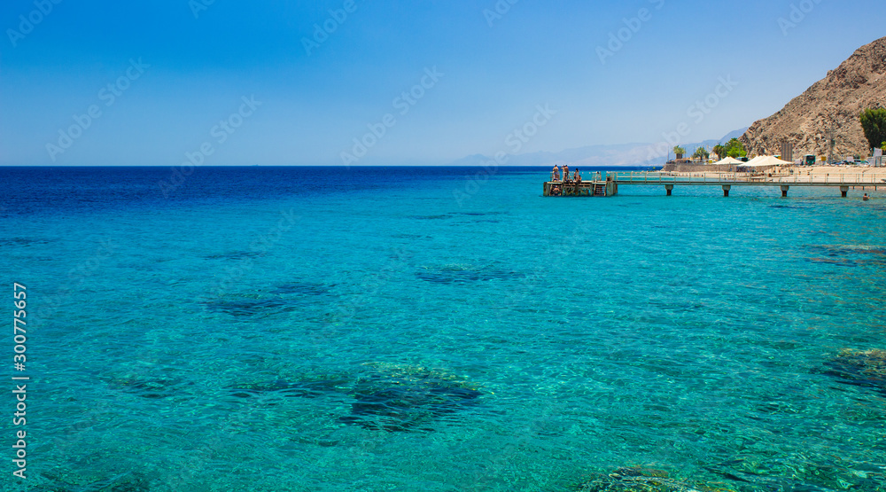 Fototapeta premium summer vacation luxury destination of Red sea bay Aqaba Gulf near Israeli city Eilat picturesque tropic shore line with coral reefs on bottom and pier on background, copy space 