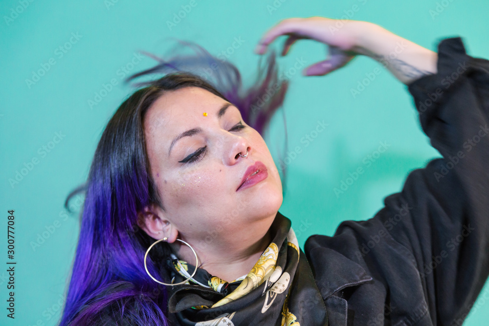 Fototapeta premium portrait of latin woman blue and purple painted hair with purple background and light sparkles