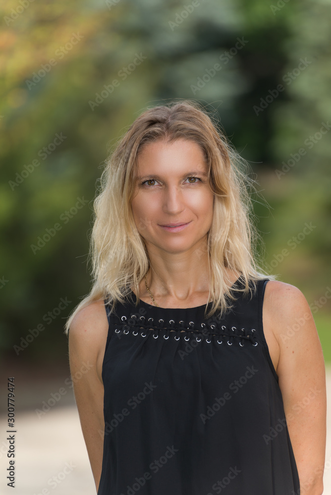 Attractive blonde young woman in a park with blurred background Attractive blonde young woman in a park with blurred background