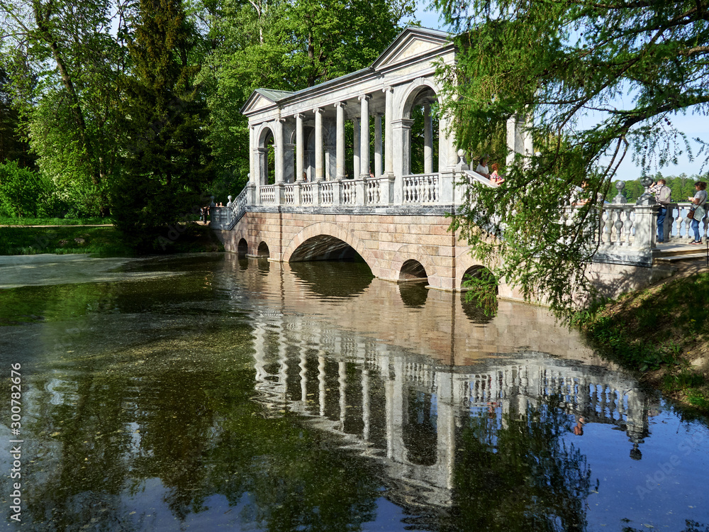 Marble bridge on pond in sunny summer day.