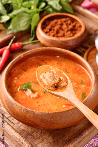 Thai red chicken curry in wooden bowl