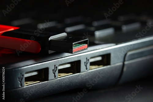 Flash drive in USB port of computer notebook in darkness. Concept of technological advances in computer data recording systems.