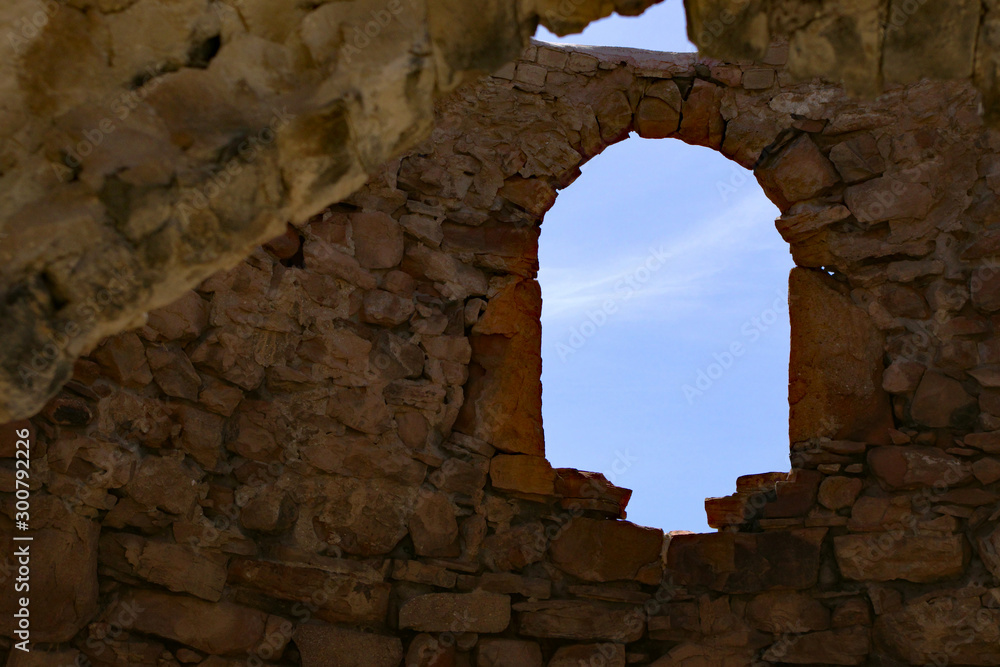 View of the sky through an arched window of an old stone shelter