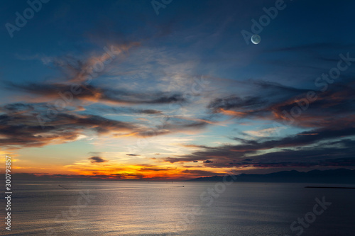月と暁に染まる海と雲