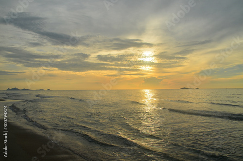 A picturesque tropical yellow coloured nimbostratus cloudy coastal sunrise seascape in a grey sky. Thailand.