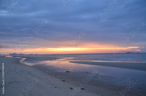 A threatening stormy but picturesque tropical orange and grey coloured cloudy coastal sunrise seascape.
