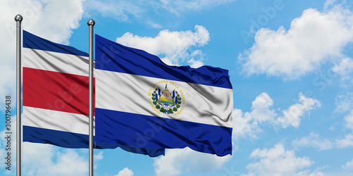 Costa Rica and El Salvador flag waving in the wind against white cloudy blue sky together. Diplomacy concept, international relations.