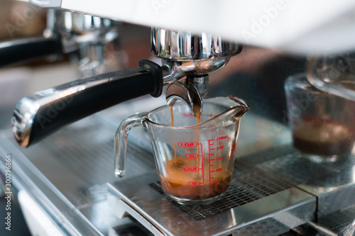 Coffee in measuring cup on a coffee machine