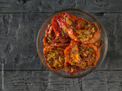 Top view of a glass bowl of sun-dried tomatoes on a black table. Vegetarian food.