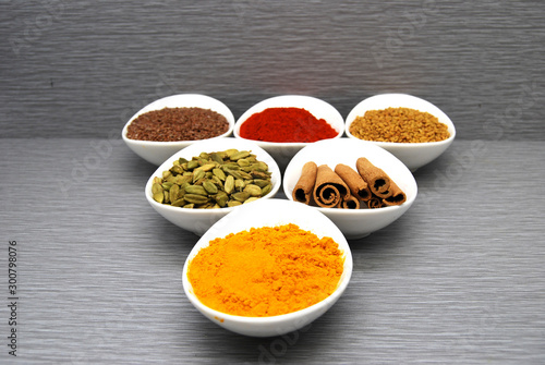 Fototapeta Naklejka Na Ścianę i Meble -  Healthy Spices Flax Seed, Chili Powder,  Fenugreek, Turmeric, Cardamom, and Cinnamon in a triangle