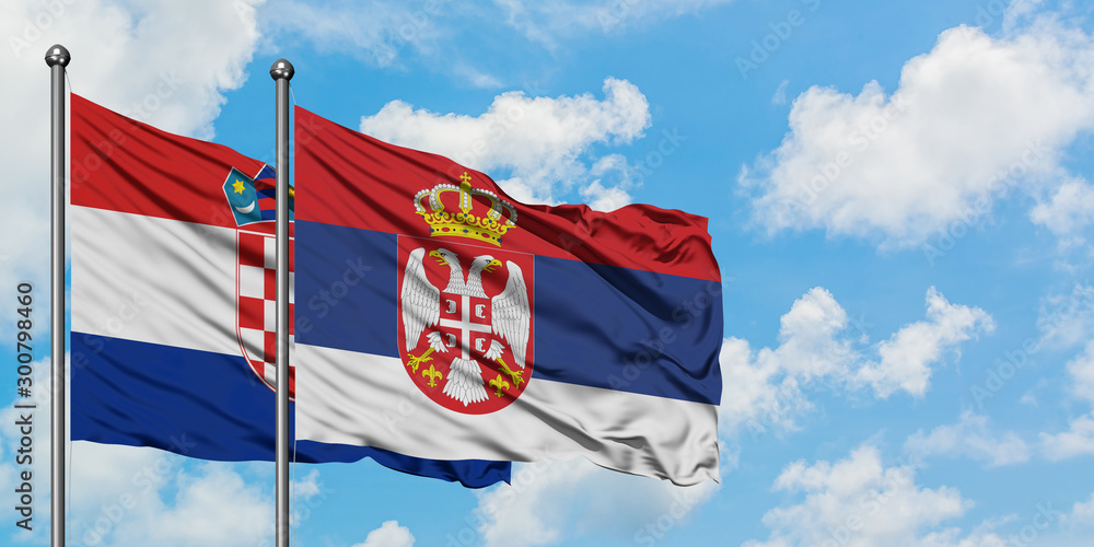 Naklejka premium Croatia and Serbia flag waving in the wind against white cloudy blue sky together. Diplomacy concept, international relations.