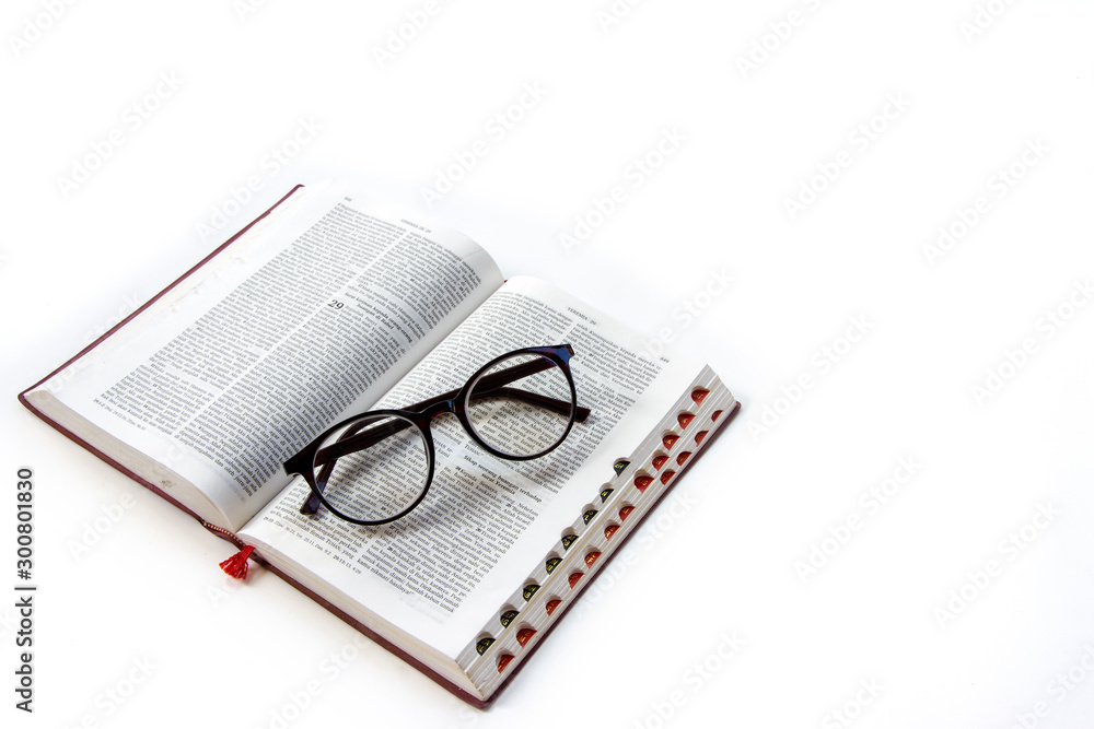 Open holy bible in bahasa Indonesia on white background with glasses Open holy bible in bahasa Indonesia on white background with glasses