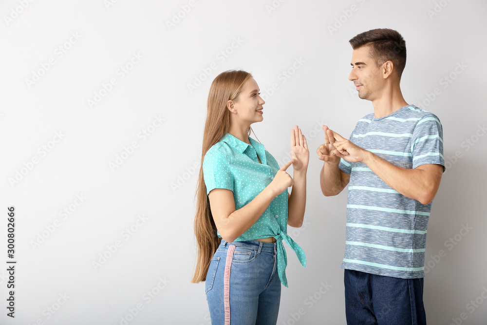 Young deaf mute couple using sign language on white background Young deaf mute couple using sign language on white background