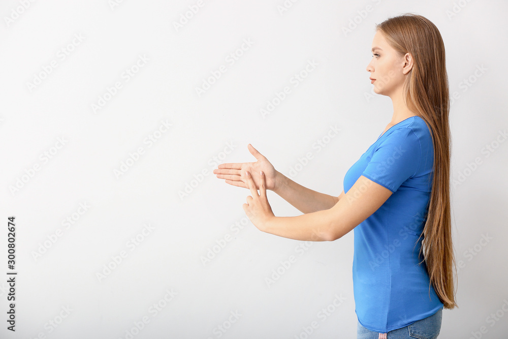 Young deaf mute woman using sign language on white background Young deaf mute woman using sign language on white background