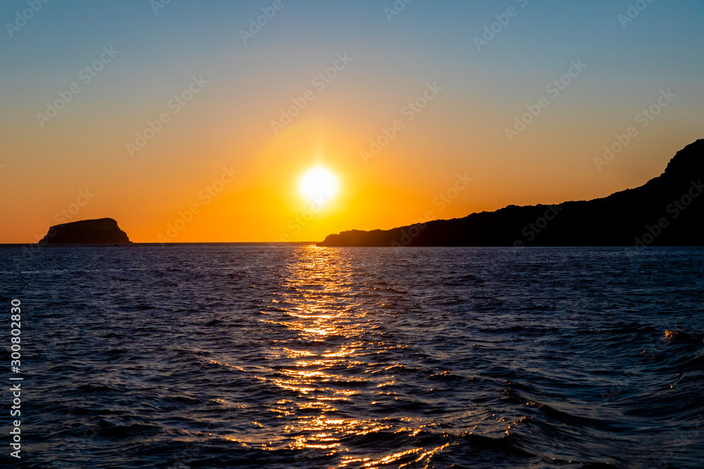 A vibrant sunset with Boats on the Aegean Sea in the Greek Islands