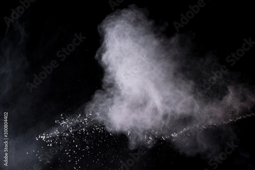 Freeze motion of white color powder exploding on dark background. 