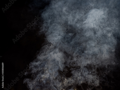 Puffs of white smoke in blurred dynamics on a dark background. Studio photography