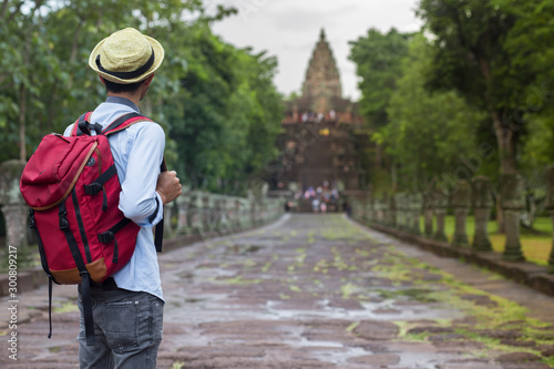 Tourist man with red backpack standing  at Prasat Phnom Rung in Phnom Rung Historical Park that important Khmer ancient monument in Buriram province, Thailand. photo