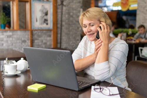 A woman with a laptop works in a cafe, she watches social networks.