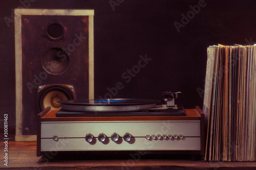 Vintage turntable audio column and vinyl records on a black background. Retro style