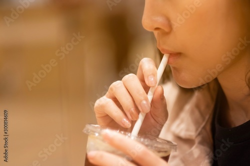 The girl uses a paper straw to suck coffee in cafe