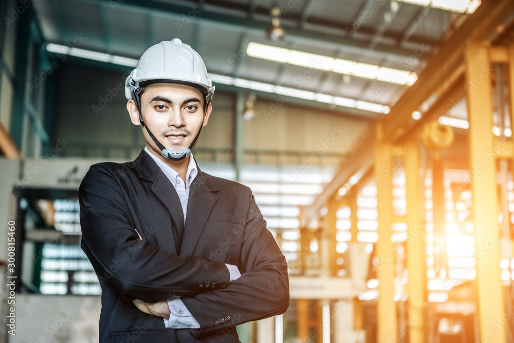 Engineer or business man wearing safety helmet standing beside of the machine in front of heavy duty factory shop floor. Factory industries concept. Engineer or business man wearing safety helmet standing beside of the machine in front of heavy duty factory shop floor. Factory industries concept.