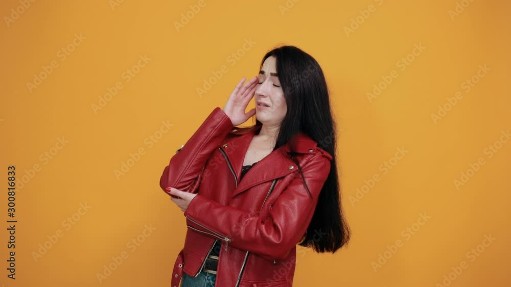 Tired disconcerted young woman in casual clothes having headache, putting hands on temple isolated on orange background in studio. People sincere emotions, lifestyle concept. Tired disconcerted young woman in casual clothes having headache, putting hands on temple isolated on orange background in studio. People sincere emotions, lifestyle concept.