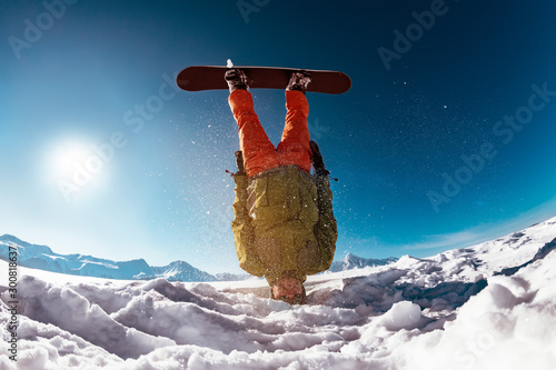 Snowboarder stands on head against mountains