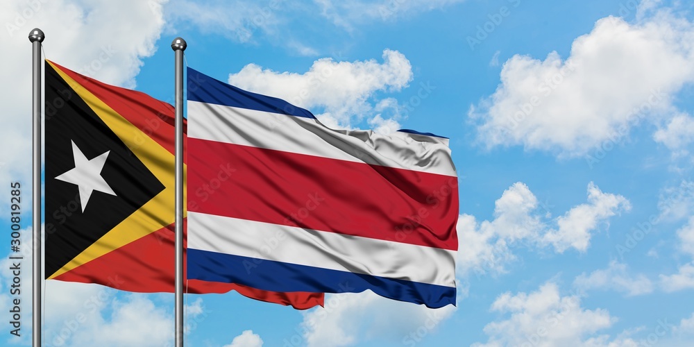 East Timor and Costa Rica flag waving in the wind against white cloudy blue sky together. Diplomacy concept, international relations.