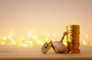 religion concept of of jewish holiday Hanukkah with wooden dreidels (spinning top) and chocolate coins over wooden table and bokeh lights background