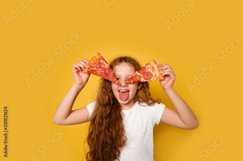 Crazy curly girl holds two slices of pizza near her eyes and sticks out her tongue.