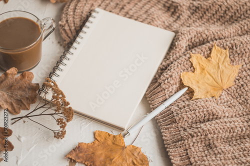 Autumn background with a notebook, pen, a cup of coffee and a sweater. Autumn planning.