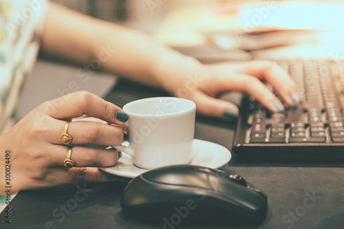Woman hand holdding coffee cup with working table