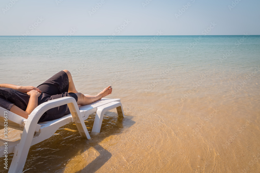 Vacation on tropical beach Woman's legs on the beach bed with clear ocean water Vacation on tropical beach Woman's legs on the beach bed with clear ocean water