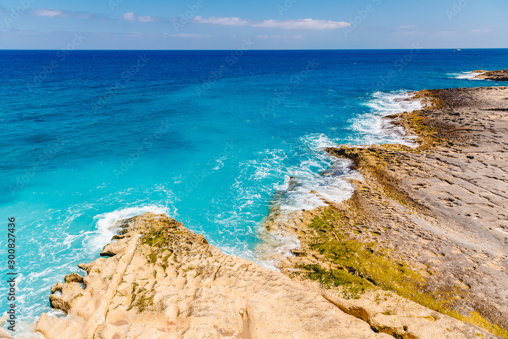 Blue emerald sea water with large stones beach. Rocky shore transparent turquoise bottom Malta