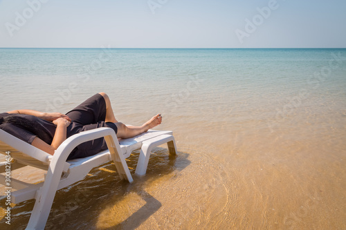 Vacation on tropical beach Woman s legs on the beach bed with clear ocean water
