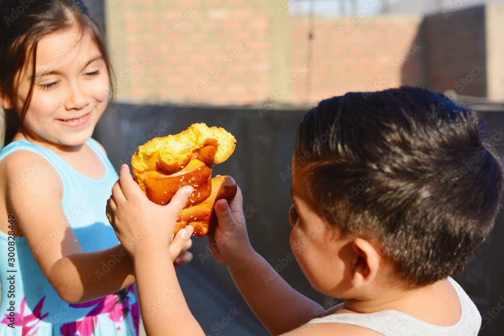 Latin kids eating tantawawa - typical sweet bread for All Saints Day.