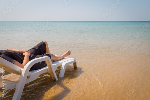 Vacation on tropical beach Woman s legs on the beach bed with clear ocean water